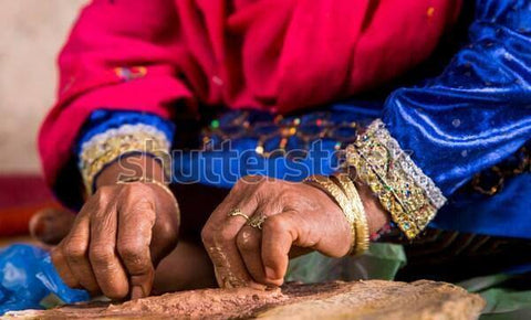 Hands of a woman in traditional attire crafting handmade Bukhoor incense